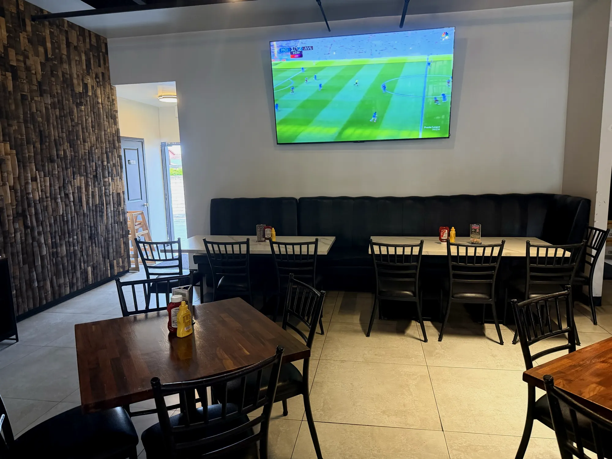Banquette seating beneath a large TV showing soccer